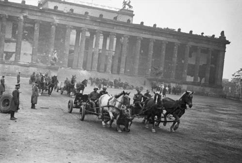 Schwarz Weiß Aufnahme einer Siegesparade im Lustgarten Berlin zum Kriegsende. Soldaten fahren in Pferdekutchen.