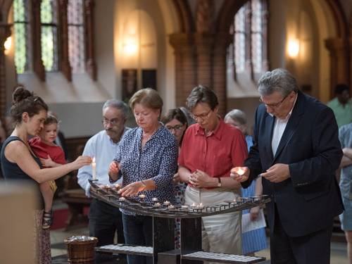 Ralf Wieland zündet mit anderen zusammen Kerzen in einer Kirche an.