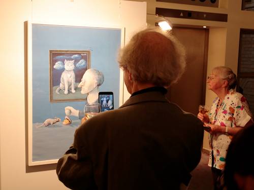 Menschen betrachten eine Karikatur in einer Ausstellung.