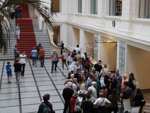 Eine große Besuchergruppe steht in der Eingangshalle des Abgeordnetenhaus Berlin und hört einem Tourguide zu.