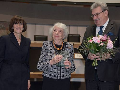 Ralf Wieland übergibt Frau Friedländer Blumen. Sie hält eine Auszeichnung in der Hand.