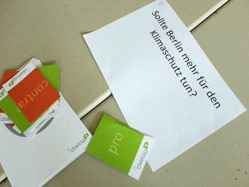 Zettel auf einem Tisch auf dem steht "Sollte Berlin mehr für den Klimaschutz tun?" daneben Abstimmungskarten