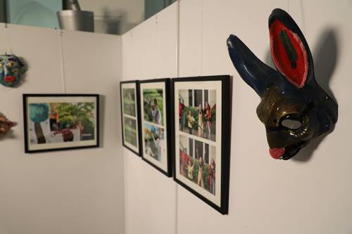 Ausstellungsobjekte hängen an der Wand, im Vordergrund eine Hasenmaske