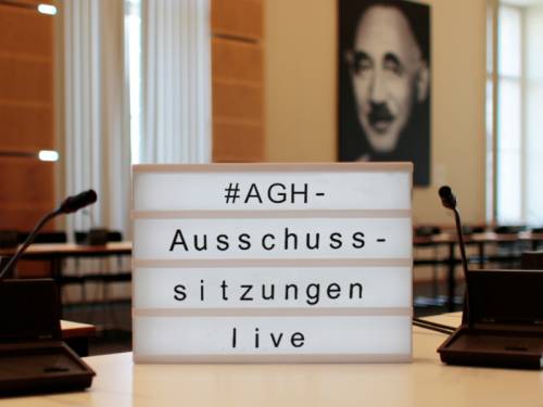 Eine Lightbox steht auf einem Tisch. Darin steht "#AGH-Ausschusssitzungen live"
