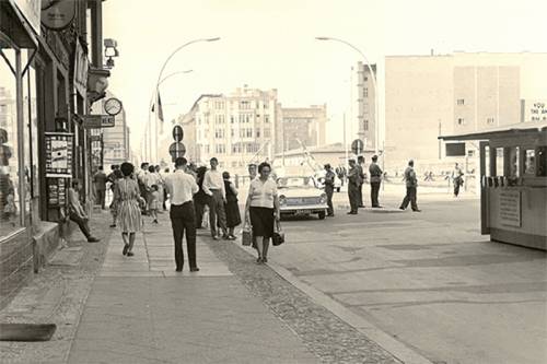Menschen laufen auf der Straße am Ort des künftigen Grenzübergangs (während der DDR) am Checkpoint Charlie.