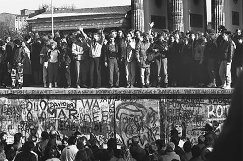 Menschen feiern auf der Mauer vor dem Brandenburger Tor die Öffnung der Mauer.